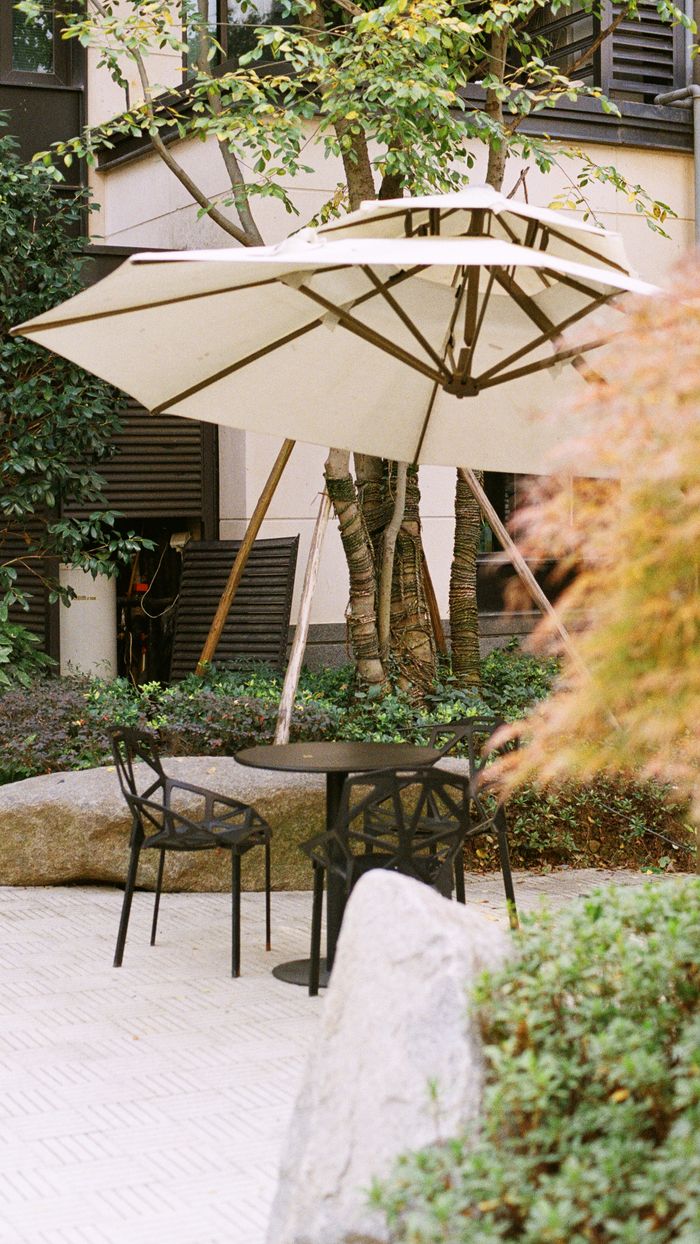 Tranquil patio area with a sunshade, table, and chairs, ideal for outdoor relaxation.