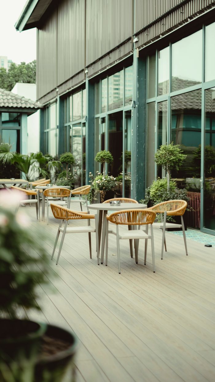 Elegant outdoor patio setup with wicker chairs and lush greenery, perfect for relaxation.
